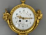 a gold clock hanging from the wall on the wall