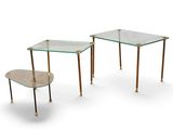 deux tables avec un plateau en verre et des pieds en métal, disposées sur un plan de travail blanc
