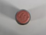 a red wax seal on a white surface with a shadow