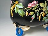 a black bowl with flowers painted on it and a blue handle
