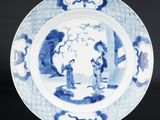 assiette bleue et blanche représentant des personnages dans un paysage