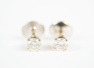 a pair of diamond stud earrings on a white background