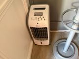a small air conditioner sitting on the floor next to a chair