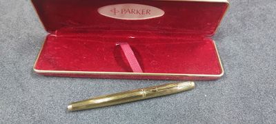 a gold pen in a red case on a blue surface