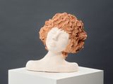 a clay sculpture of a woman ' s head on a pedestal