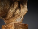 a statue of a man ' s head on top of a wooden block
