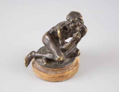 statue en bronze représentant un homme assis sur un socle en bois, les mains sur le visage