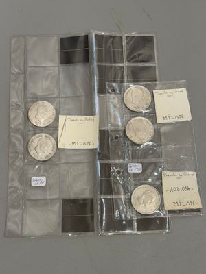 quelques pièces d'argent sont rangées dans un étui en plastique transparent posé sur une table