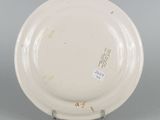 underside view of a white plate with writing on it on a metal stand
