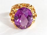 a close up of a ring with a purple stone in it