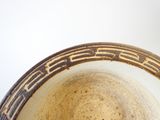 un bol marron et blanc posé sur une table