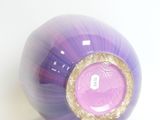 a purple ball with a gold rim sitting on a white surface