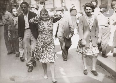 many people walking down the street in this old photo
