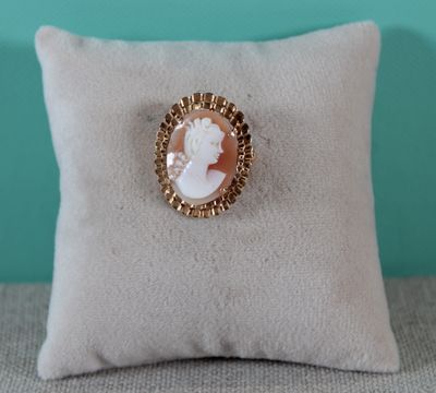 a close up of a pillow with a white and gold broochet on it