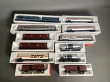 tout un tas de trains miniatures de différents modèles, rangés dans des boîtes sur la table