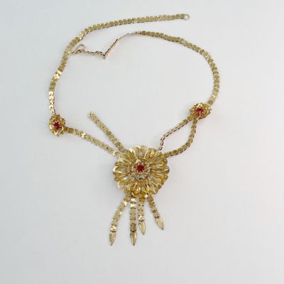 collier en or orné de pierres rouges sur fond blanc