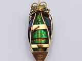 an image of a green and gold pendant with a fish on it ' s back