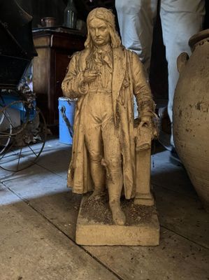 a statue of a man that is standing next to a vase