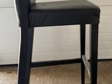 a black bar stool sitting in front of a white wall
