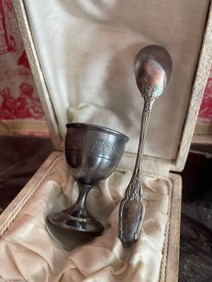 une tasse et une cuillère en argent dans un étui posé sur une table