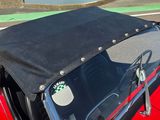 une voiture rouge au toit noir garée sur le bord de la route