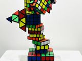 a multicolored rubik cube sculpture on a clear base