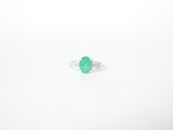 an oval emerald and diamond ring on a white background