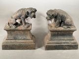 deux statues représentant un chien et un chat, posées sur un socle