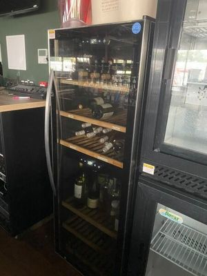 bottles of wine are lined up in a wine cooler in a restaurant
