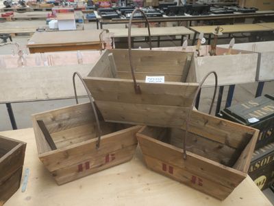 trois caisses en bois munies de poignées, posées sur une table dans un entrepôt