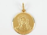 a close up of a gold plated jesus medallion on a white background
