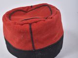 a red hat with black trim on a white surface
