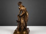 une statue antique en bronze représentant une femme tenant un panier de fleurs