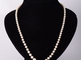 un collier de perles blanches sur un mannequin noir