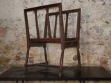 two wooden chairs sitting on a table in front of a brick wall