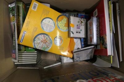 une boîte en carton remplie de livres et de papiers, posée par terre