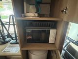 a microwave and a water tank in a small cabinet