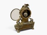 a gold clock with a mirror on top of it