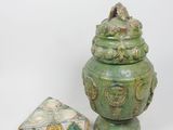 un vase vert orné d'un oiseau, à côté d'une boîte