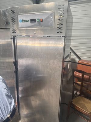 a man that is standing next to a stainless steel refrigerator