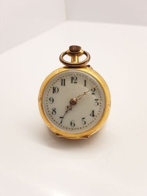 une montre de poche en or posée sur une surface blanche