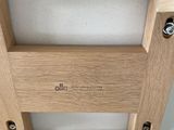 the back of a wooden chair with a seat made of wood and white fabric