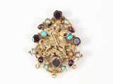 an antique gold broochle with various colored stones on a white surface