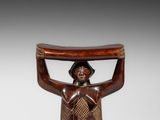 une petite sculpture en bois représentant un homme tenant un panier sur la tête