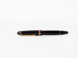 un stylo noir et or posé sur une surface blanche