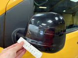 a person holding a sticker in front of a yellow car