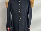 un manteau militaire noir avec des boutons dorés et des franges, posé sur un présentoir pour mannequin