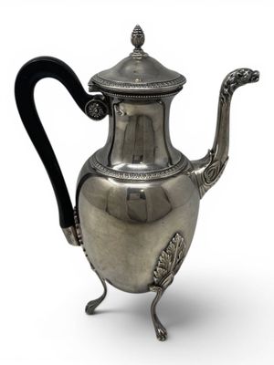 an antique silver teapot with a black handle on a stand