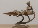 bronze statue of a woman sitting on a leaf with a bird on it