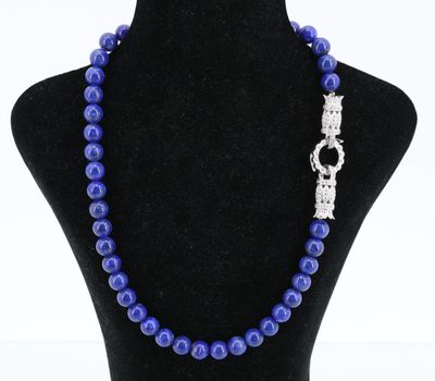 un collier de perles bleues muni d'un fermoir en argent, posé sur un mannequin